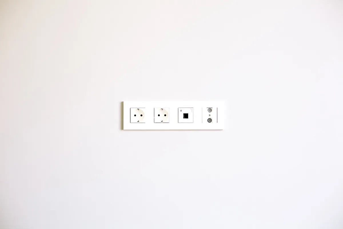 A modern wall outlet array on a bright white wall, highlighting the importance of electrical safety compliance.